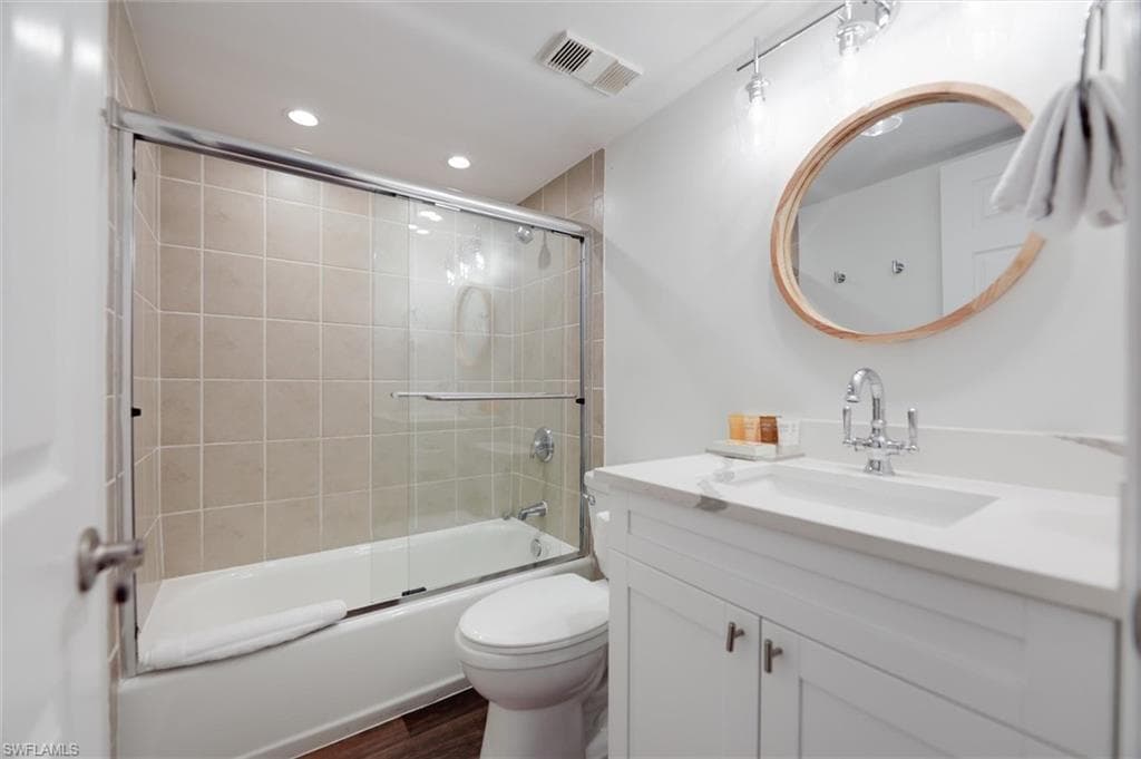Full bathroom with vanity, bath / shower combo with glass door, recessed lighting, and dark wood finished floors