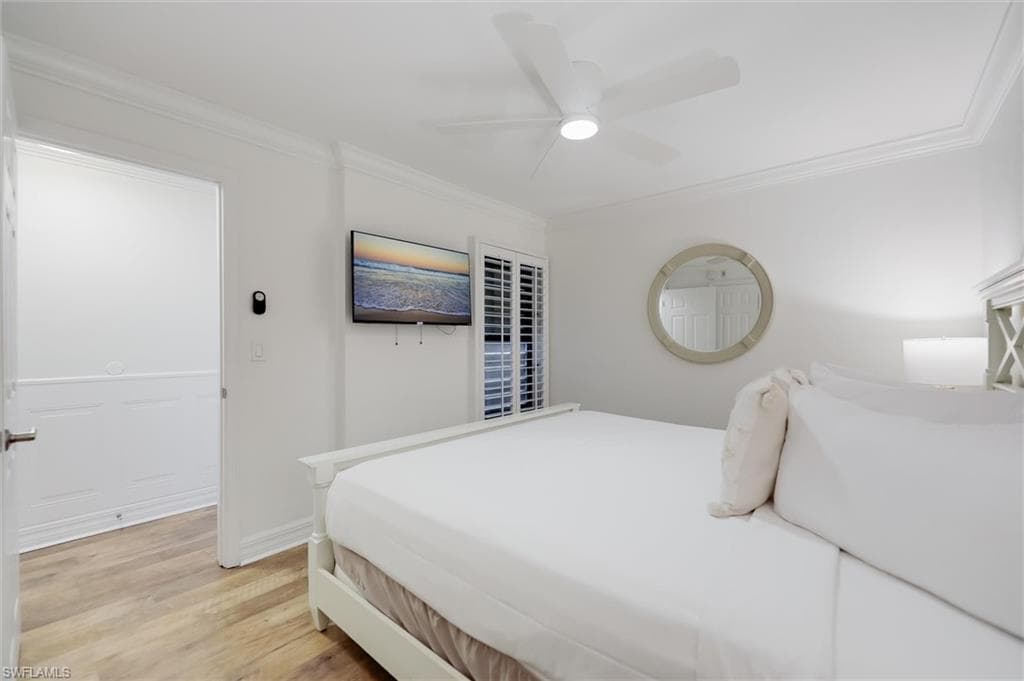 Bedroom featuring light wood-style floors, crown molding, and a ceiling fan