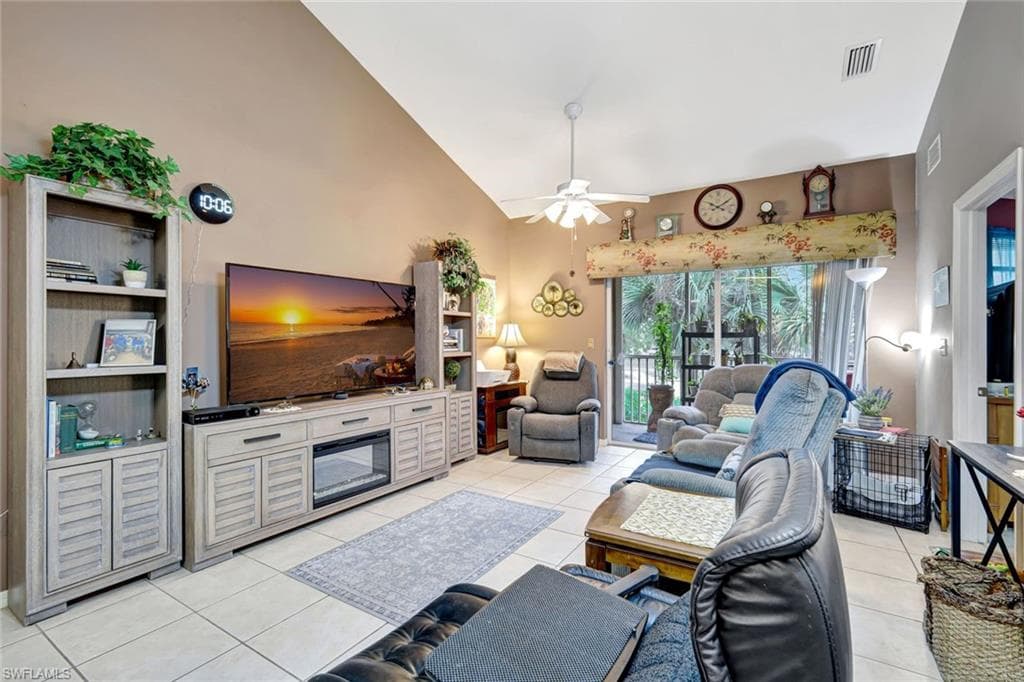 Living area featuring high vaulted ceiling, ceiling fan, and light tile patterned floors