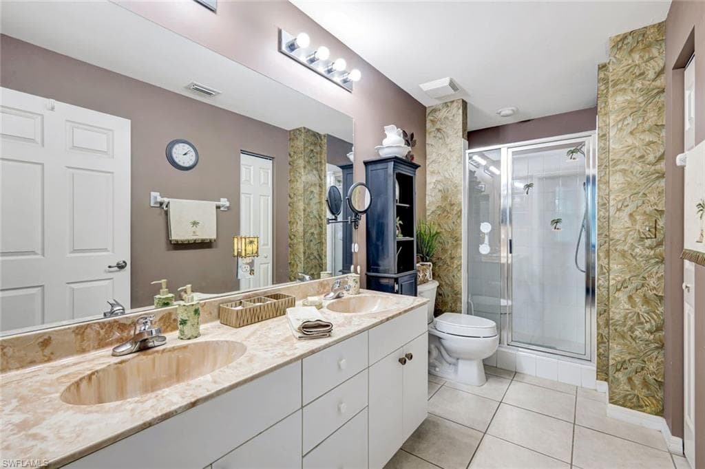 Bathroom featuring double vanity, a shower stall, and light tile patterned flooring