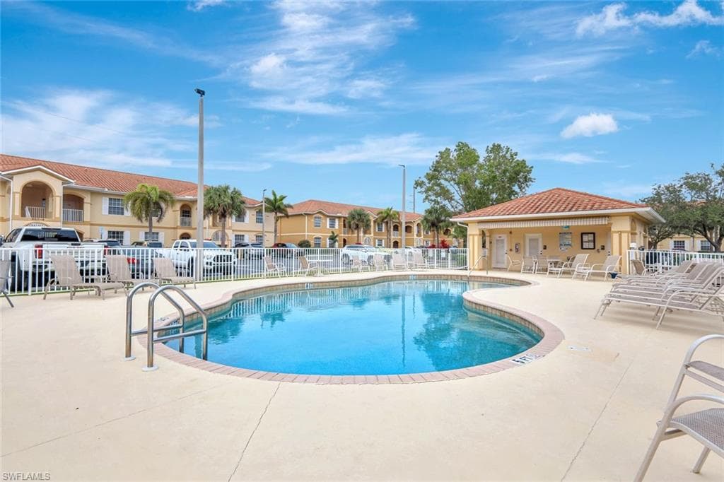 Community pool with a patio area and a residential view