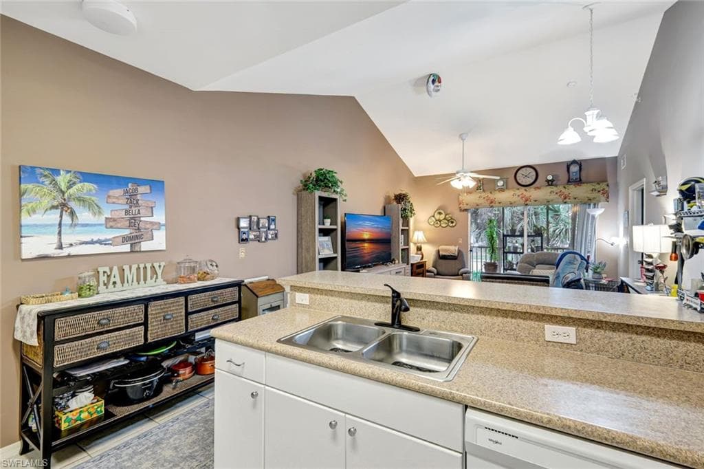 Kitchen with open floor plan, light countertops, white cabinetry, white dishwasher, and decorative light fixtures