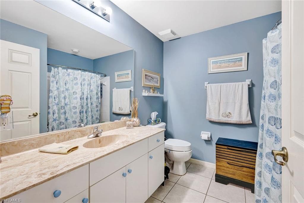 Bathroom with vanity, light tile patterned floors, and a shower with shower curtain