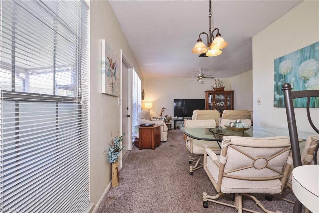 Dining area with a chandelier, carpet, and a ceiling fan