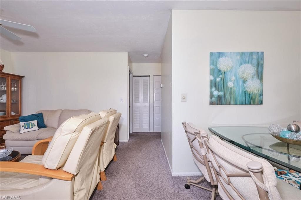 Living area with carpet flooring, ceiling fan, and baseboards