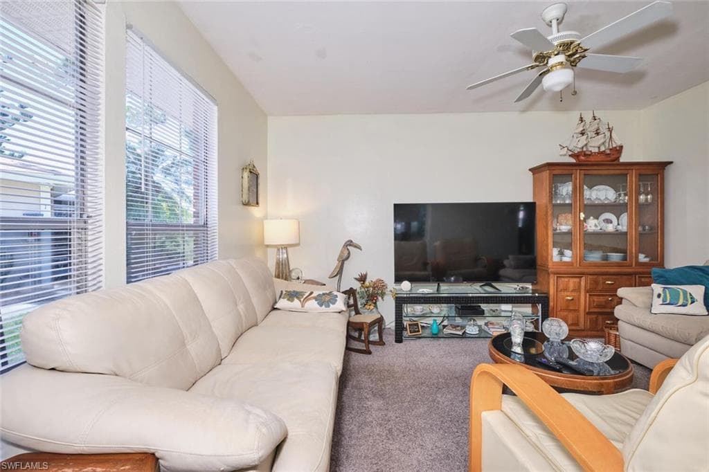 Living room featuring carpet and a ceiling fan