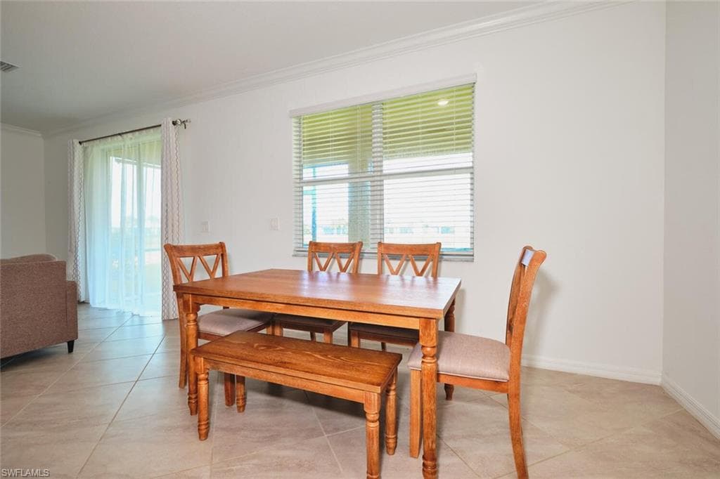 Dining room featuring crown molding and light tile patterned flooring