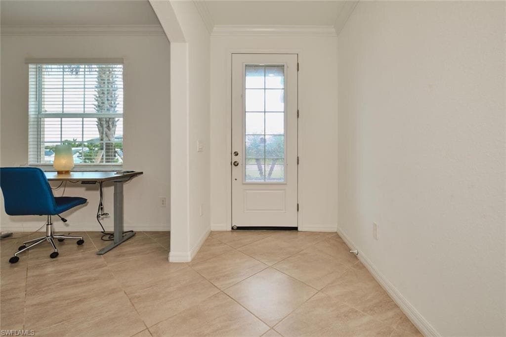 Entryway featuring crown molding, tile patterned flooring, and arched walkways