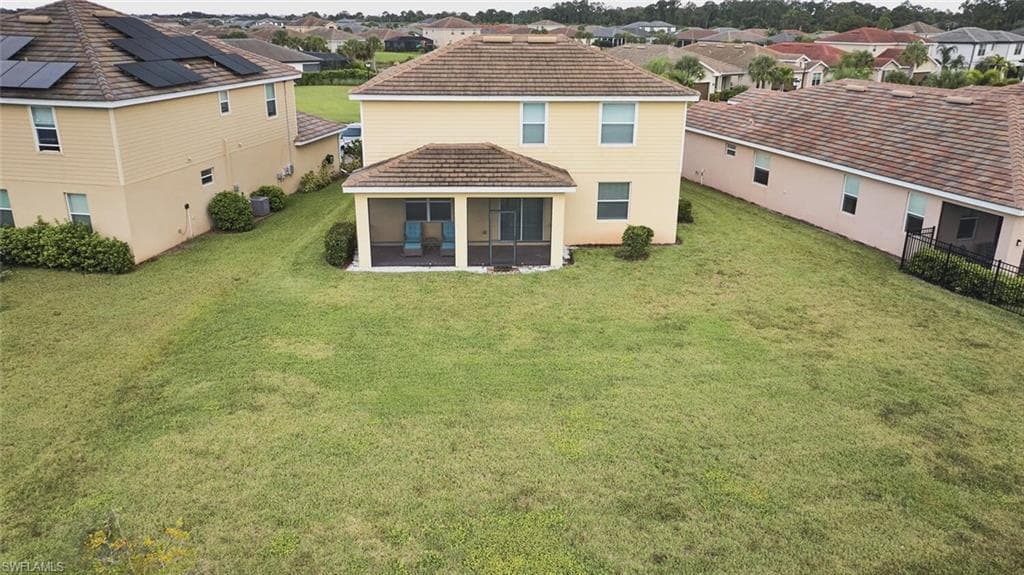 Rear view of property featuring a lawn, a residential view, and a tiled roof