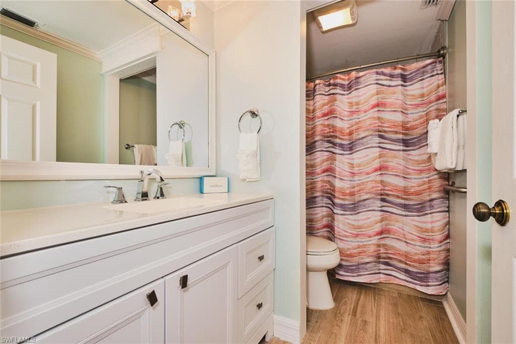 Main living area Full bath with vanity, light wood finished floors, and ornamental molding