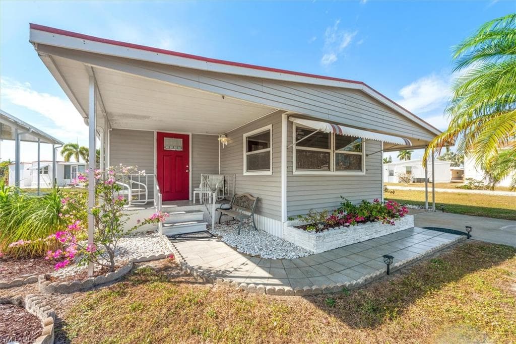 Manufactured / mobile home featuring covered porch and a front lawn