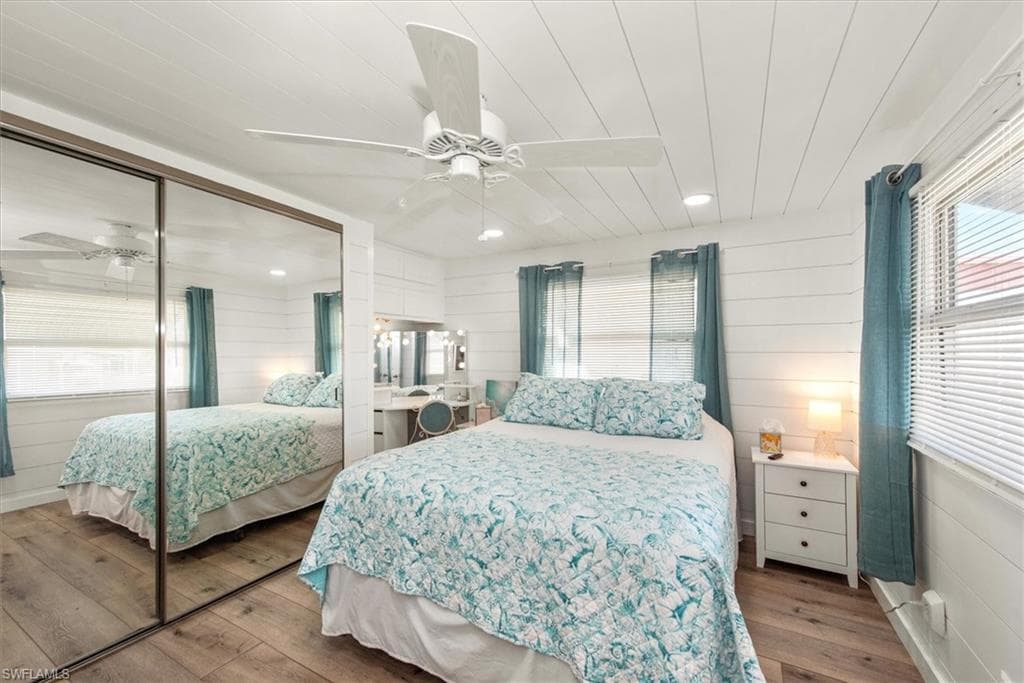 Bedroom with wood walls, ceiling fan, a closet, light wood-style floors, and recessed lighting