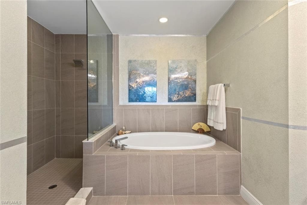 Full bath with a textured wall, walk in shower, a bath, and recessed lighting