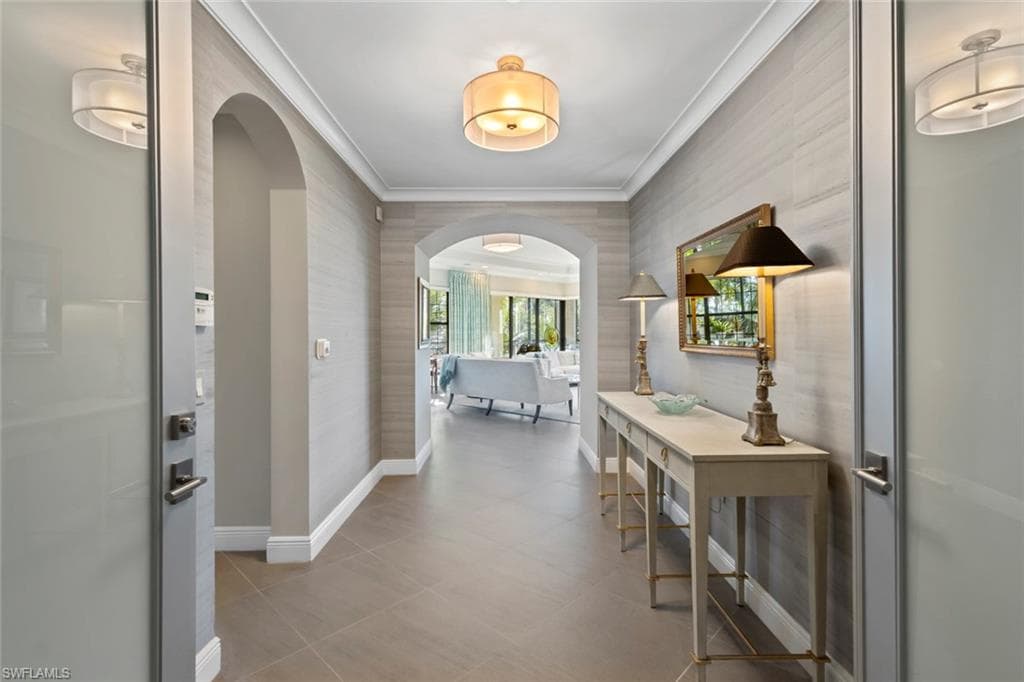 Hall with arched walkways, crown molding, and wallpapered walls