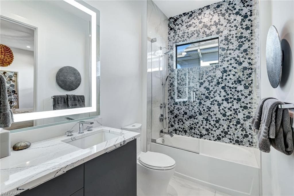 Bathroom featuring vanity and bath / shower combo with glass door