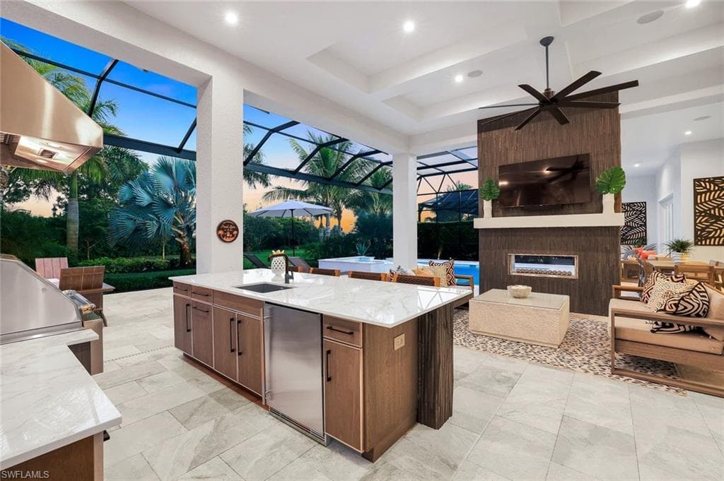View of patio / terrace featuring exterior kitchen, ceiling fan, glass enclosure, a large fireplace, and a sunroom