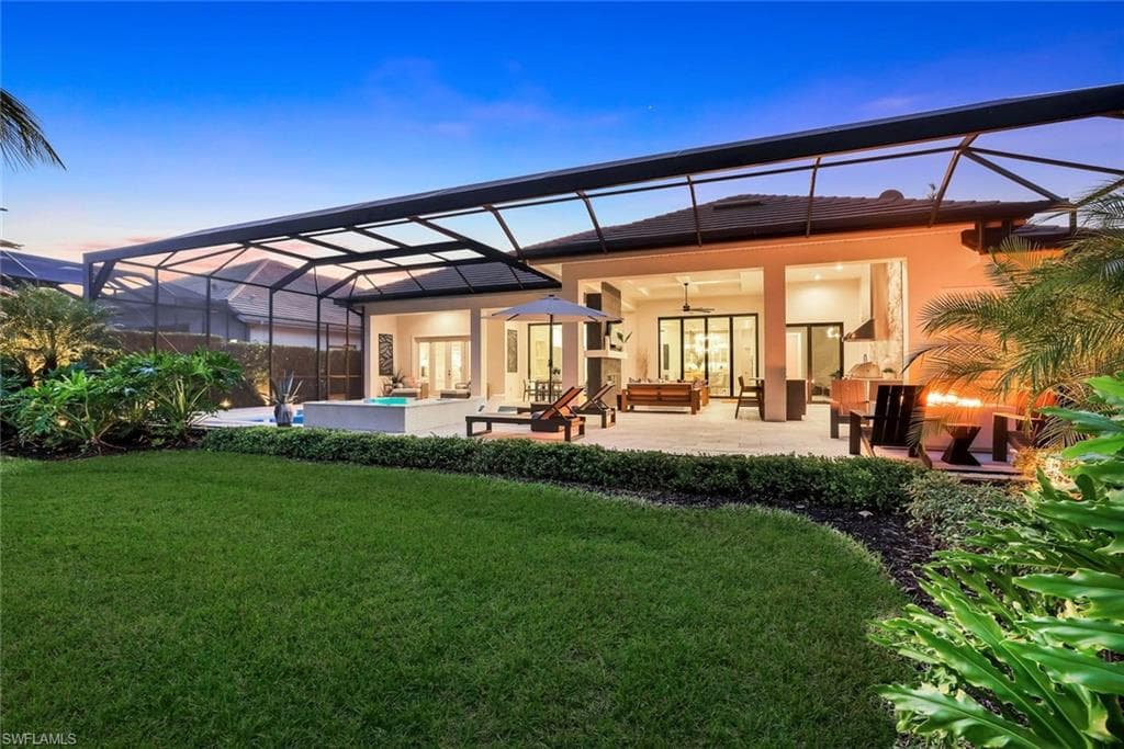 Back of property at dusk with a lanai, a sunroom, ceiling fan, and an outdoor hangout area
