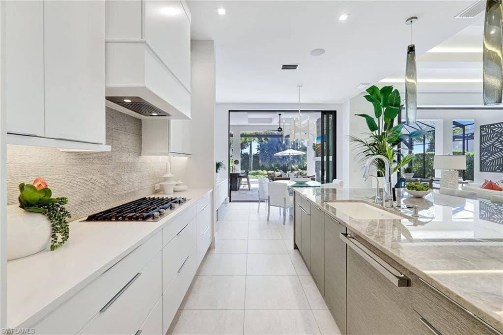 Kitchen featuring modern cabinets, pendant lighting, white cabinetry, decorative backsplash, and recessed lighting