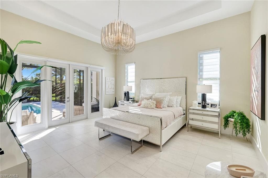 Bedroom featuring access to outside, light tile patterned flooring, a chandelier, and a raised ceiling