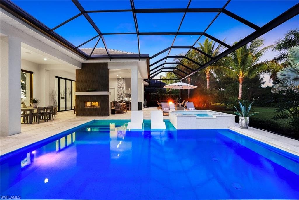 View of pool with a fireplace, a pool with connected hot tub, a sunroom, a patio area, and glass enclosure