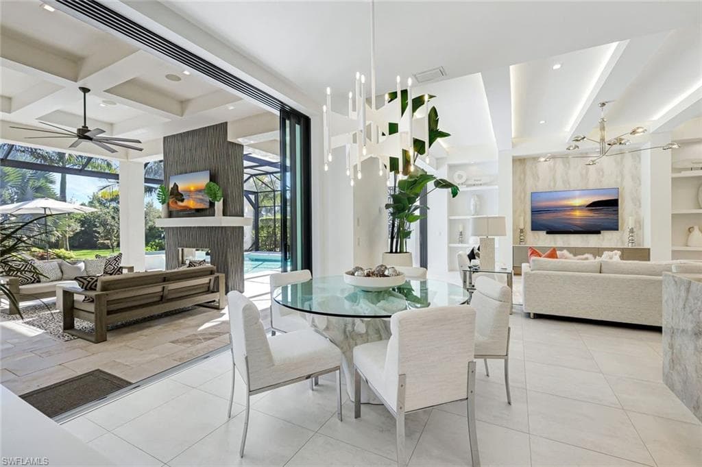 Tiled dining space featuring beam ceiling, built in shelves, coffered ceiling, a sunroom, and ceiling fan