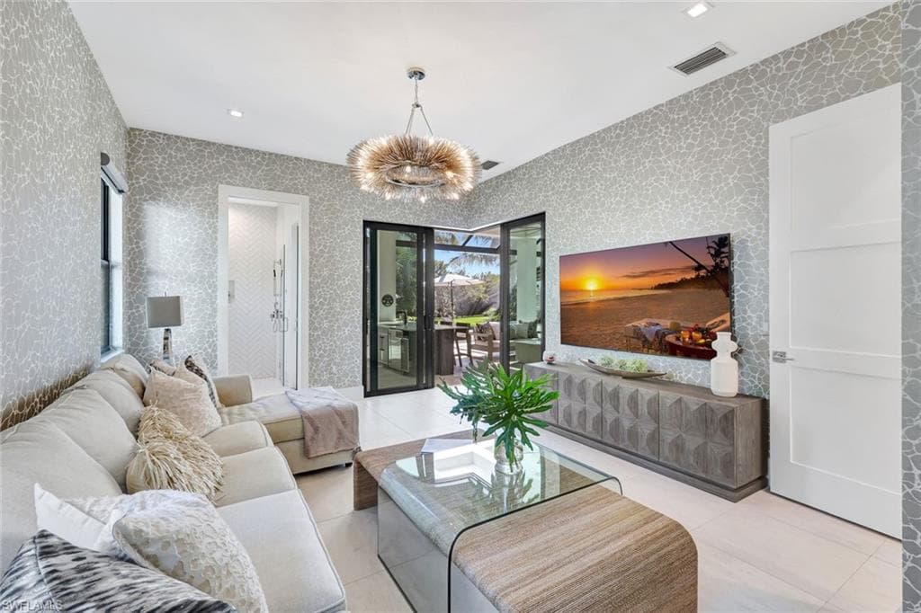 Tiled living room with a chandelier and wallpapered walls