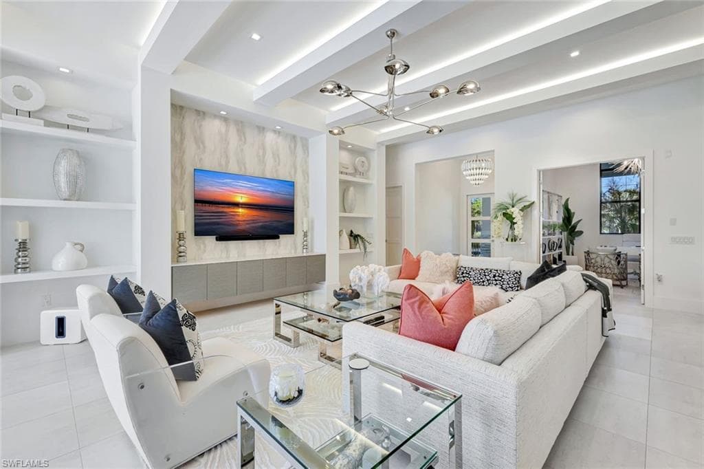 Living room featuring built in shelves, light tile patterned flooring, beam ceiling, a chandelier, and recessed lighting