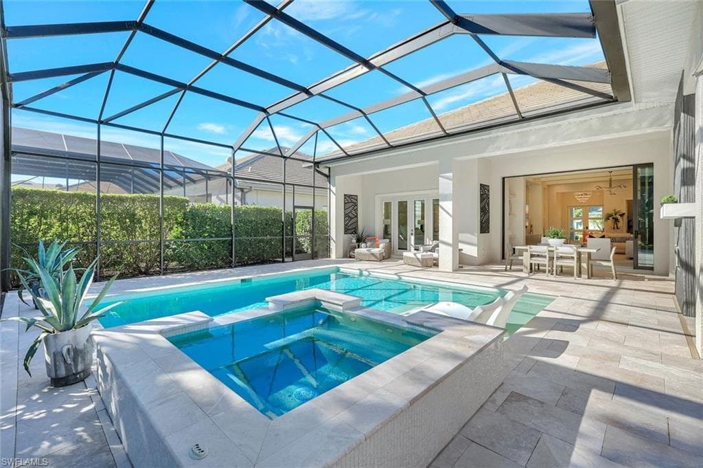 View of pool featuring a sunroom, a pool with connected hot tub, a lanai, and a patio area