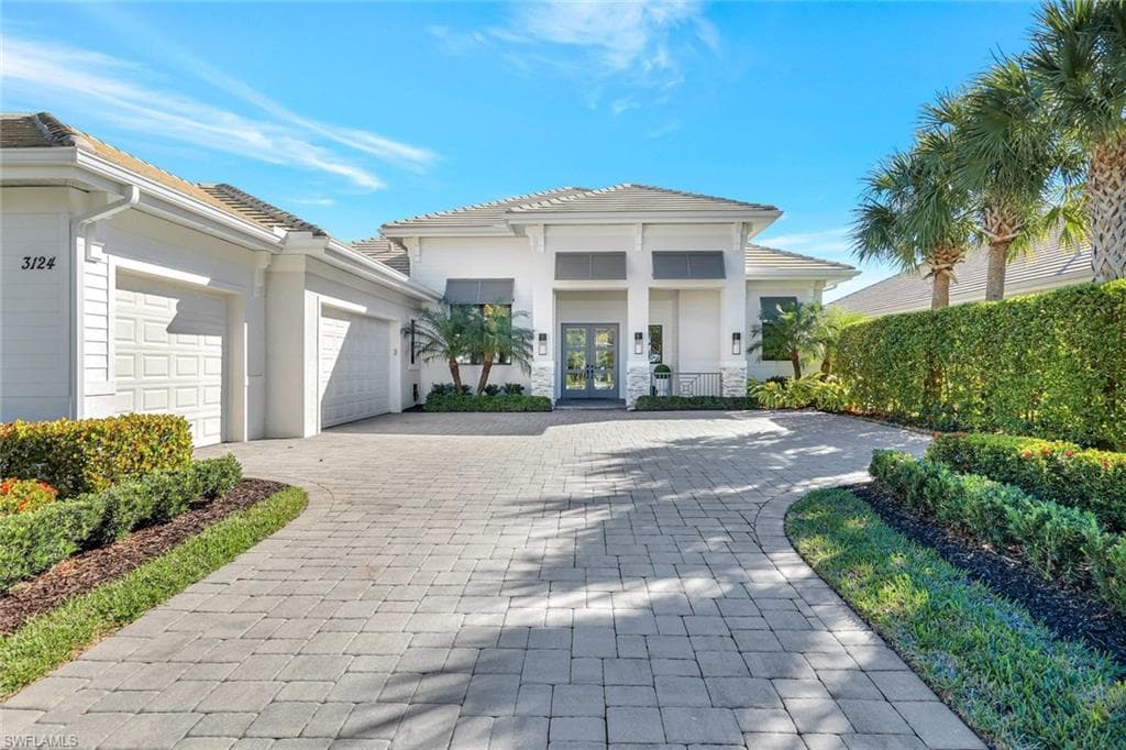 View of front of home featuring decorative driveway, french doors, a garage, and stucco siding