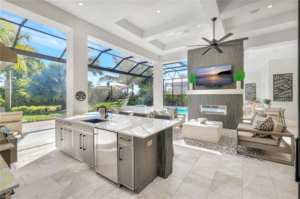 View of patio with area for grilling, a ceiling fan, a sunroom, and glass enclosure