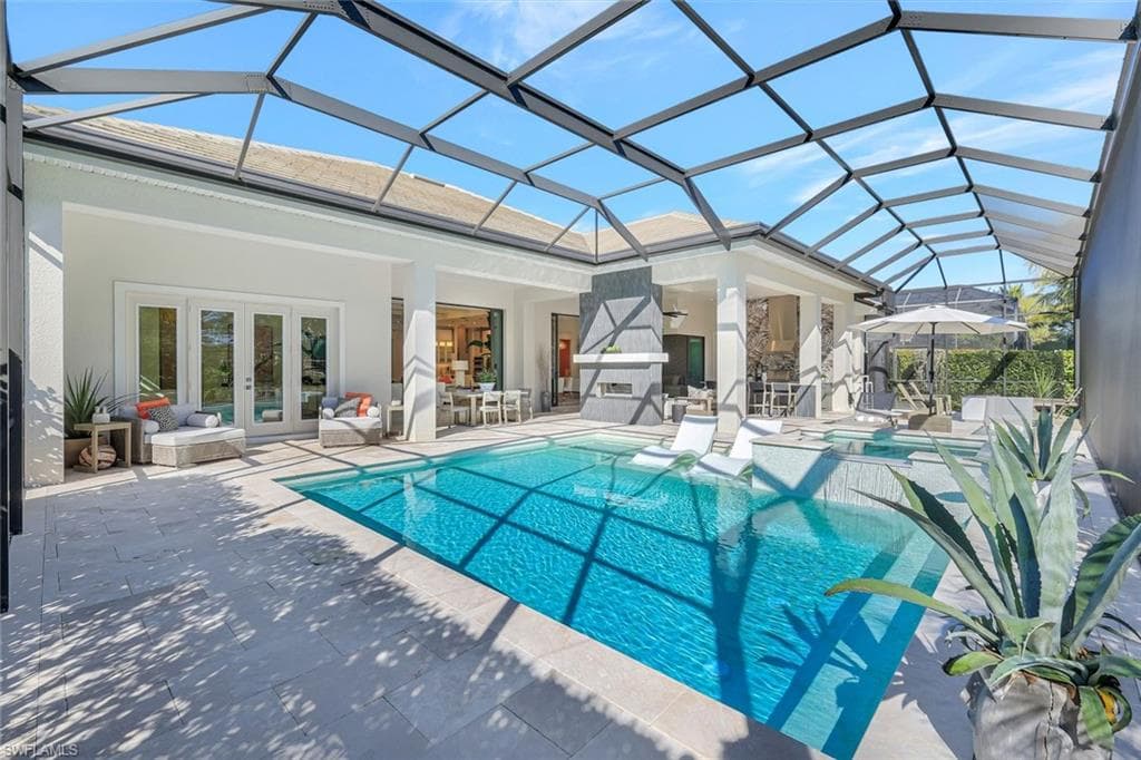 View of pool with a sunroom, glass enclosure, a patio area, and a pool with connected hot tub