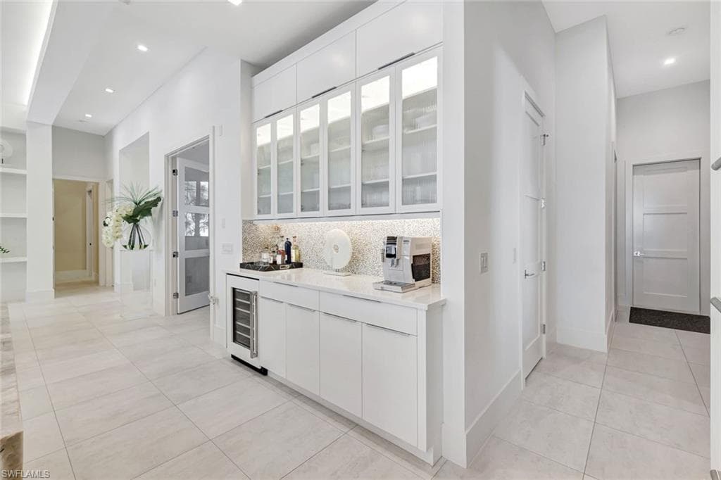 Bar area with white cabinets, glass insert cabinets, modern cabinets, light tile patterned floors, and recessed lighting