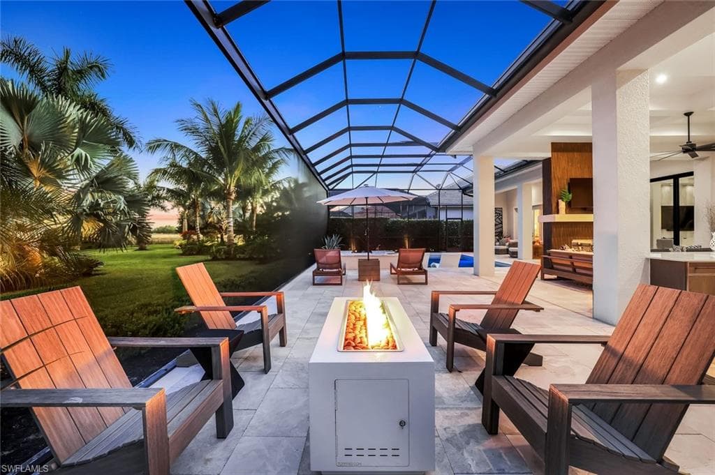 Patio terrace at dusk featuring a patio, a ceiling fan, a sunroom, and glass enclosure