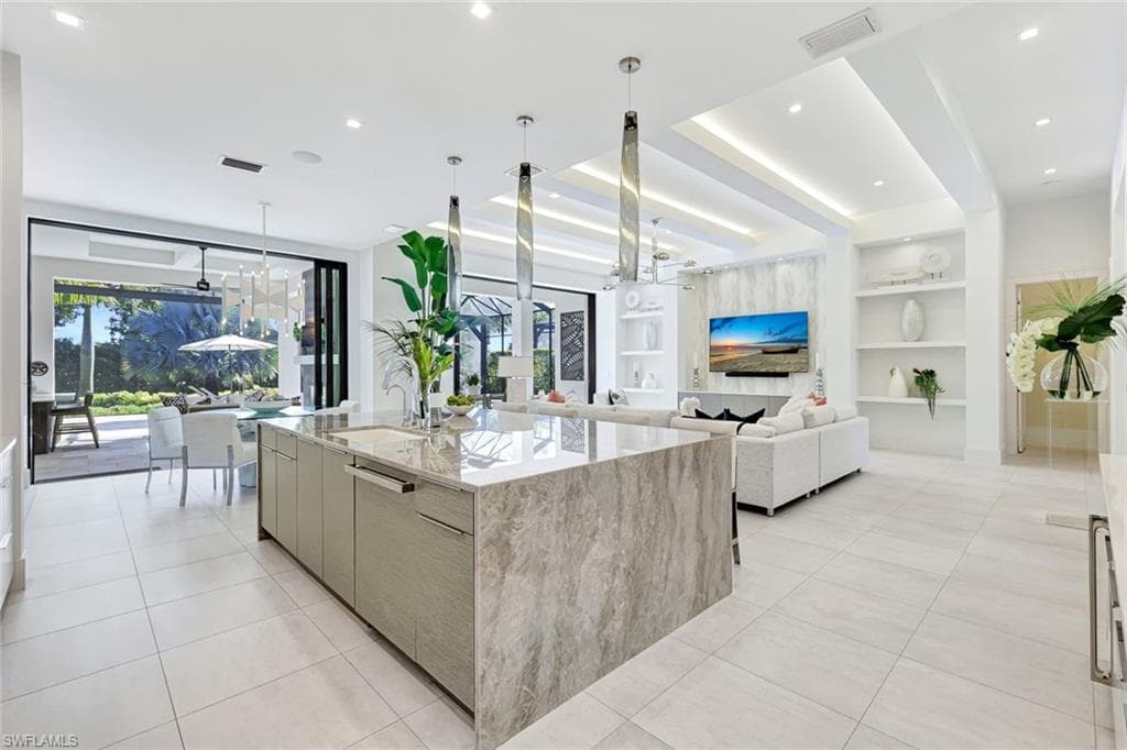 Kitchen with built in shelves, a chandelier, light stone countertops, modern cabinets, and decorative light fixtures