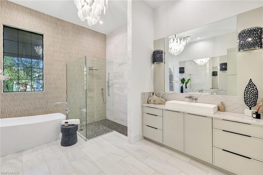 Bathroom with a soaking tub, a chandelier, a stall shower, and vanity