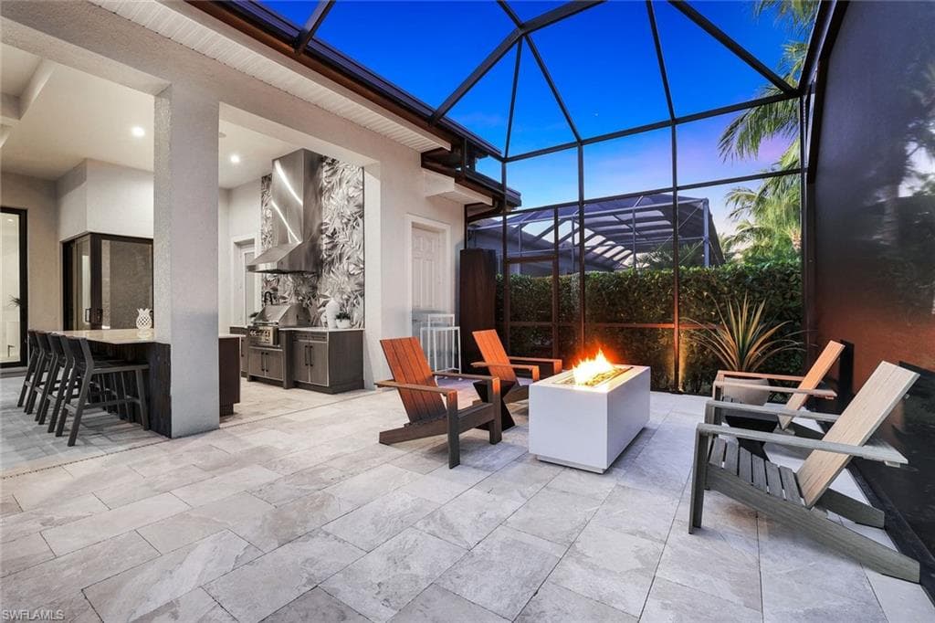 View of patio / terrace with glass enclosure, an outdoor fire pit, a sunroom, area for grilling, and a bar