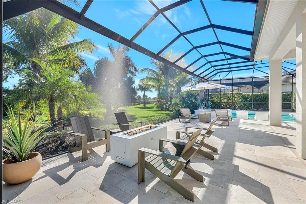 View of patio with glass enclosure, a sunroom, a fire pit, and an outdoor pool