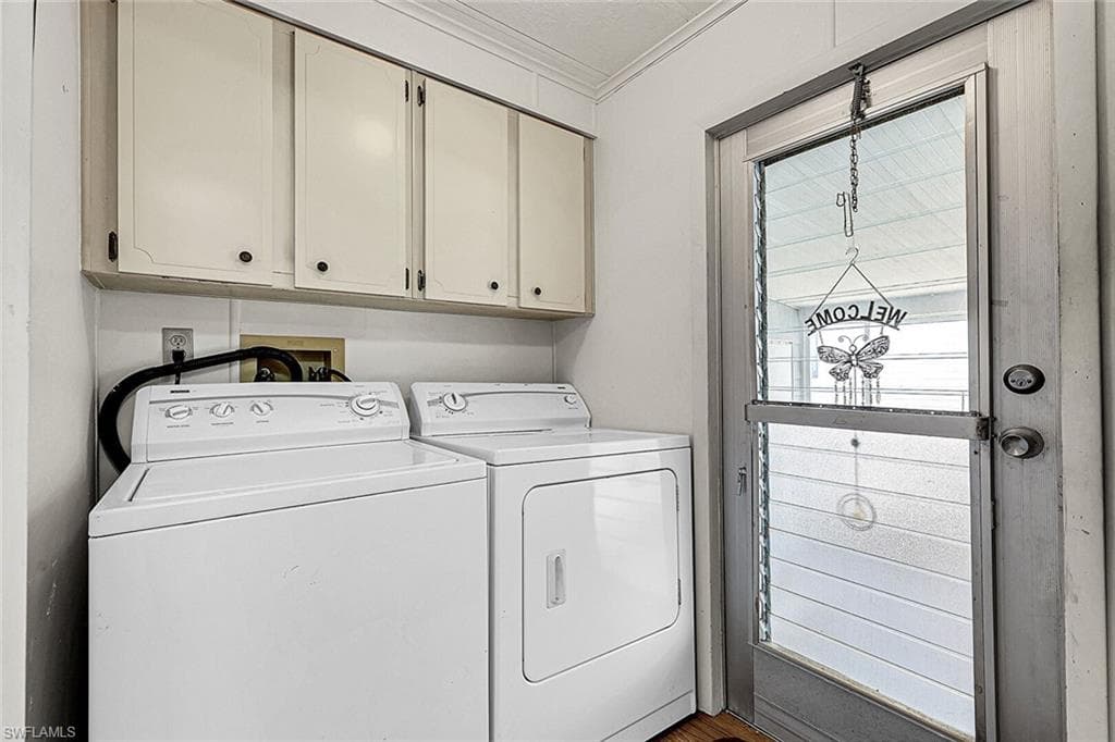 Laundry room featuring ornamental molding, washer and clothes dryer, cabinet space, and wood finished floors