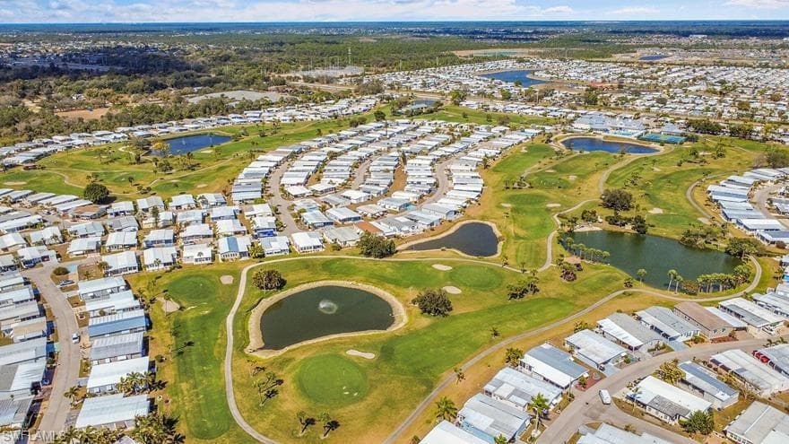 Aerial view of residential area featuring a nearby body of water and a golf club
