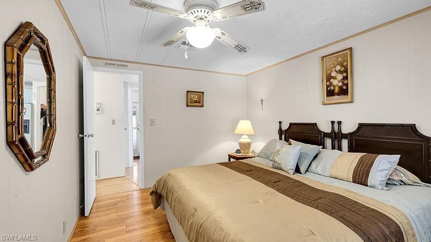 Bedroom with light wood-style flooring, ornamental molding, and a ceiling fan