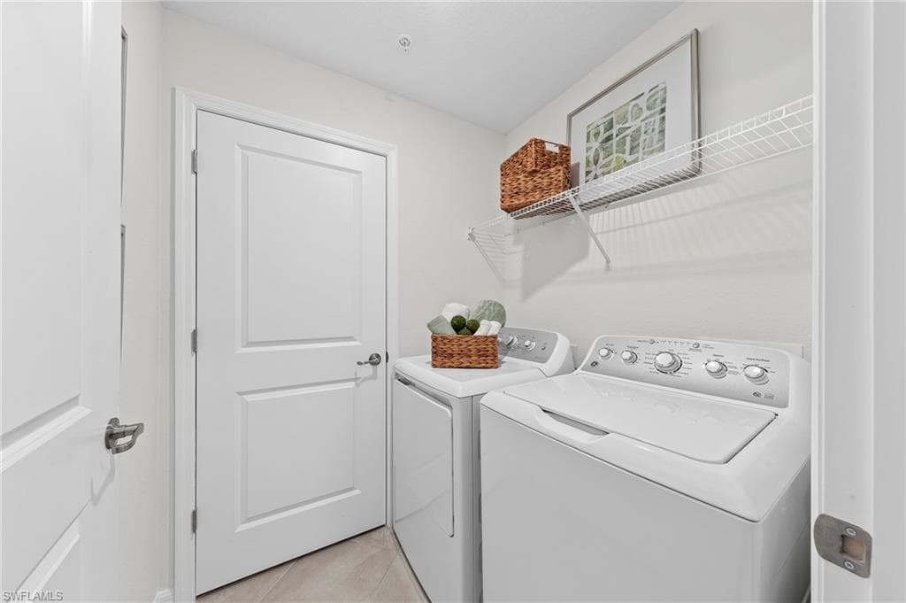 Laundry area featuring separate washer and dryer and light tile patterned flooring