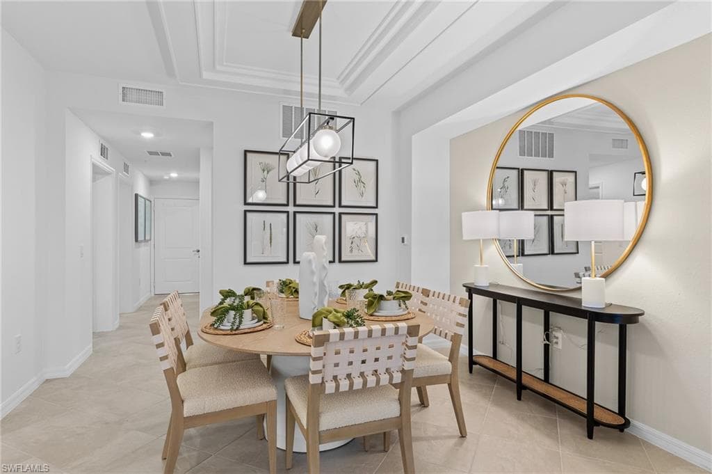 Dining area featuring a tray ceiling, ornamental molding, and light tile patterned flooring