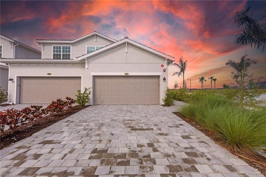 View of front facade featuring decorative driveway, a garage, and stucco siding
