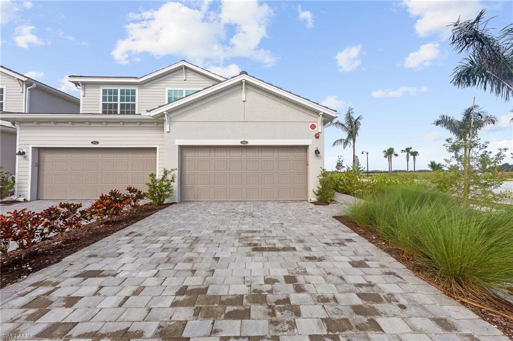 View of front of house featuring decorative driveway, a garage, and stucco siding