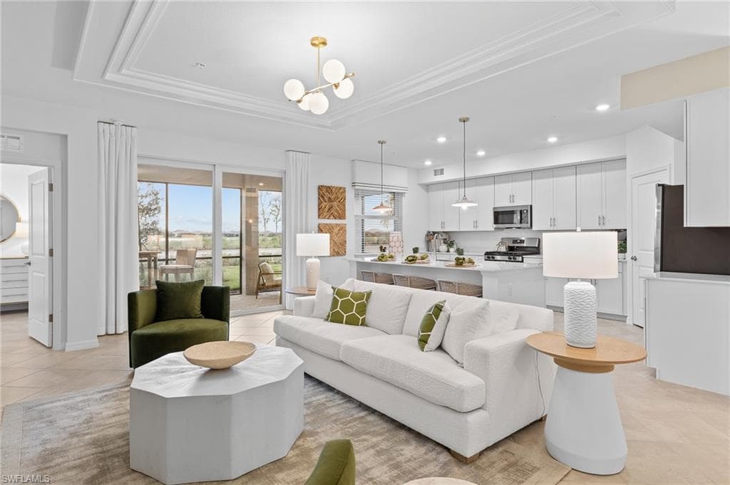 Living room featuring light tile patterned floors, a tray ceiling, a chandelier, and recessed lighting