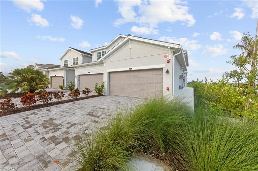 View of front facade featuring stucco siding and decorative driveway