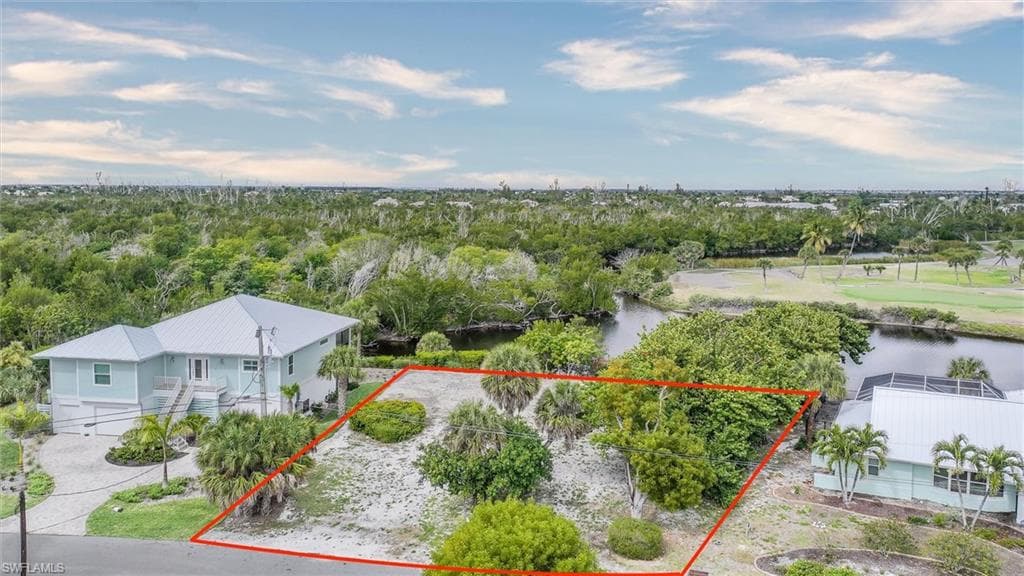 Aerial view of property and surrounding area featuring property parcel outlined and a nearby body of water