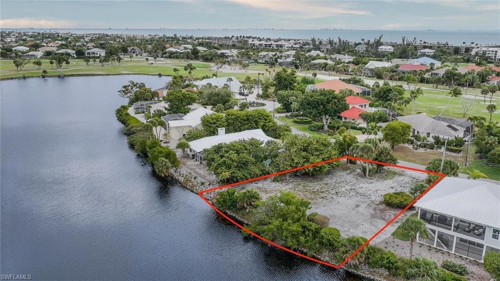 Aerial view of residential area with a nearby body of water and property parcel outlined