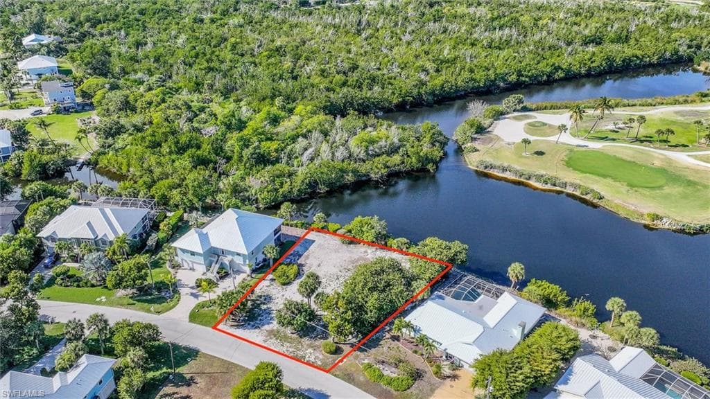 Aerial view of property and surrounding area with property parcel outlined, a large body of water, and a local golf course