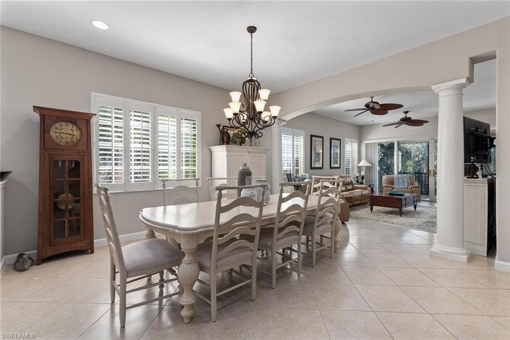 Dining space with ornate columns, a ceiling fan, light tile patterned floors, and healthy amount of natural light